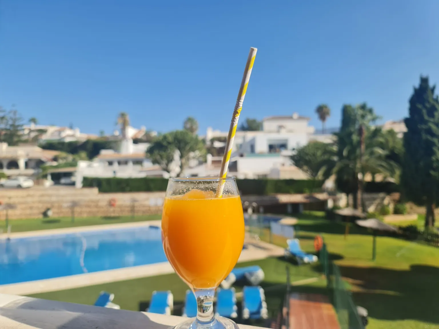 Poolmiljø med terrasse og tennisområde i baggrunden